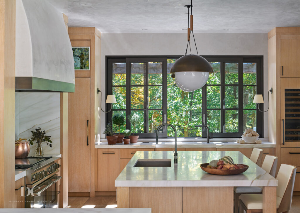 A custom kitchen with Holly Hunt stools, Allied Maker pendant lights, and light wood custom cabinetry by Rock Ridge Fine Cabinetry and Millwork